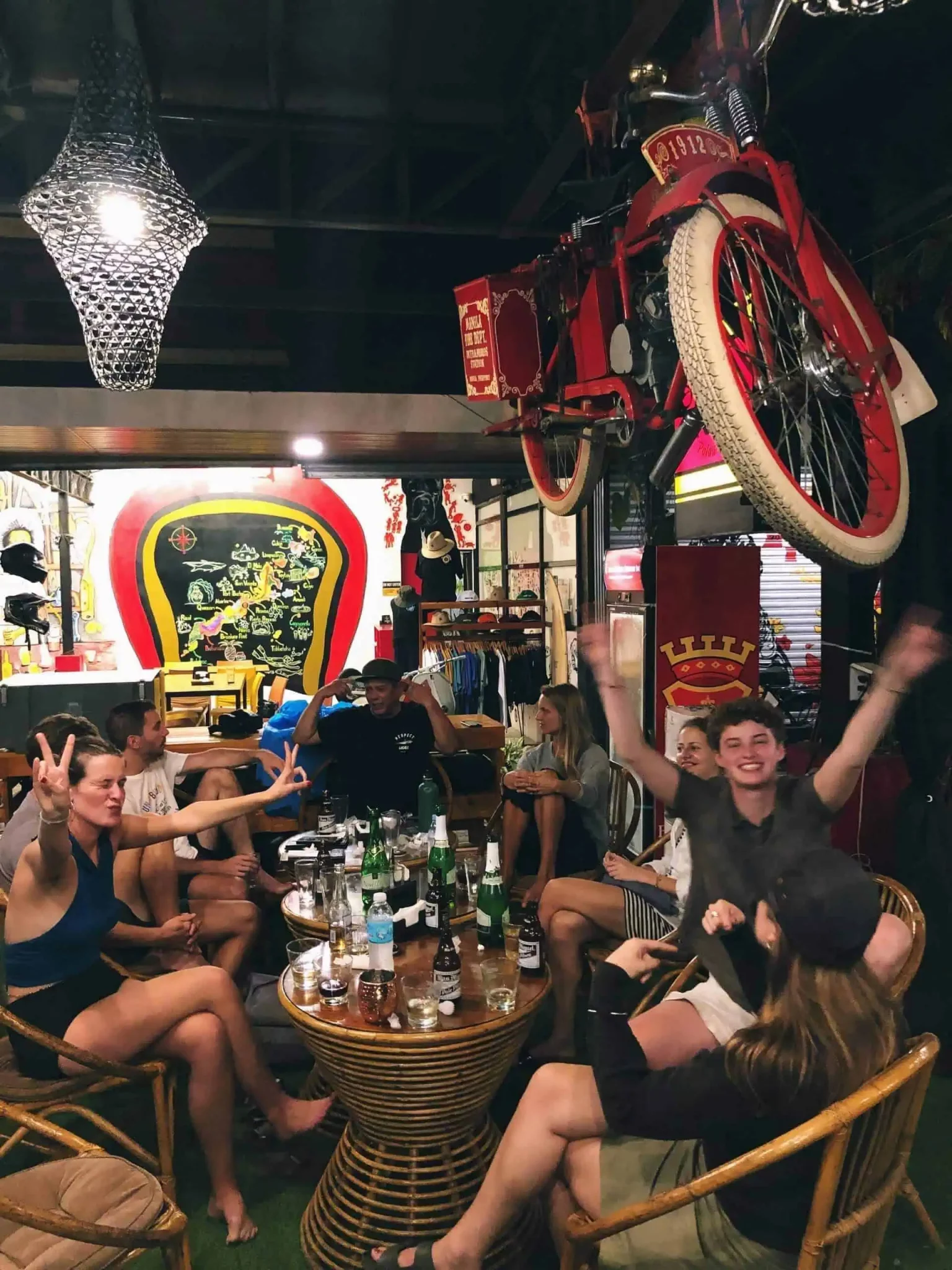 Guests enjoying drinks at Cafe Moto Hostel under a vintage red bike hanging from the ceiling.